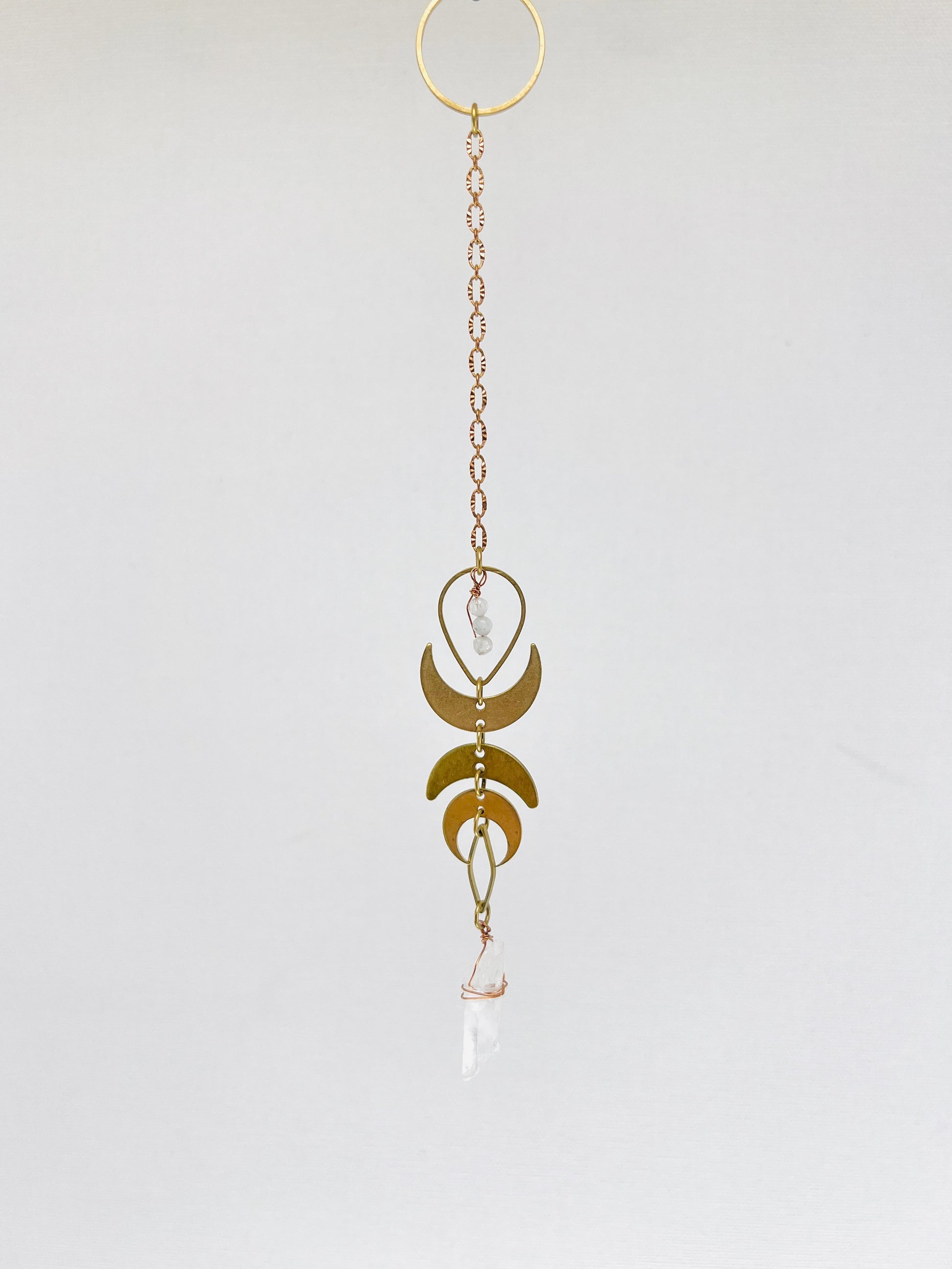Pendulum hanging art A photo of three dimensional art, meant to hang on the wall. It is a combination of crystals, metals and wood and looks similar to a dream catcher. It helps to attract your best life, through the crystals meanings.there are also crescent moons and other brass charms on it.