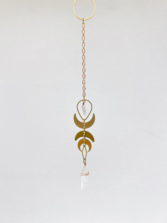 Pendulum hanging art A photo of three dimensional art, meant to hang on the wall. It is a combination of crystals, metals and wood and looks similar to a dream catcher. It helps to attract your best life, through the crystals meanings.there are also crescent moons and other brass charms on it.