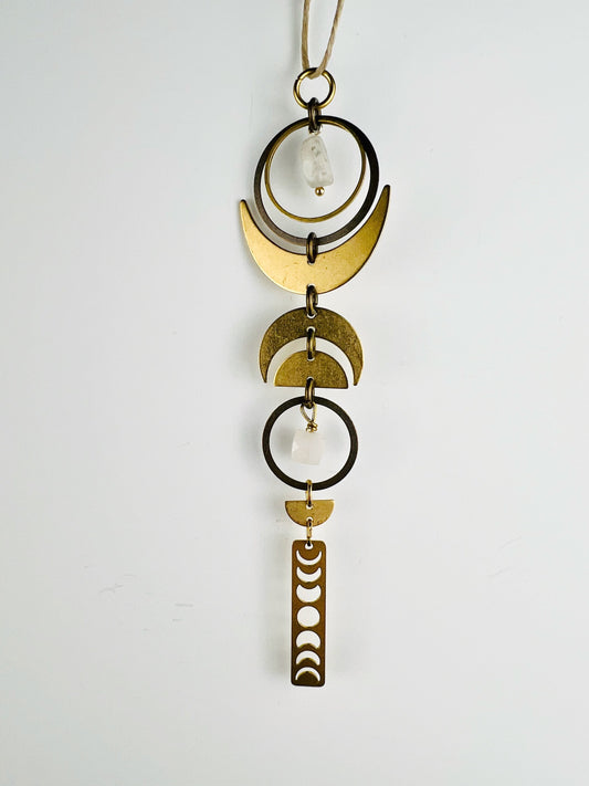 hanging rearview mirror brass and bronze charm with gold crescent moons, half circles and a moon phase charm on a white background. Kunzite and Pink Aventurine manifestation charm, handcrafted intentional décor designed to support love, self-worth, and emotional healing.