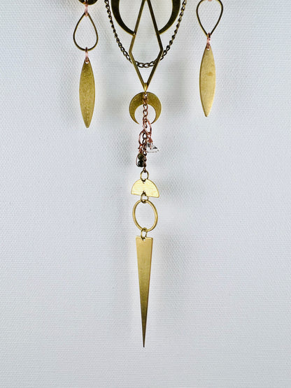Gold colored metal shapes and wire wrapped Green tourmaline and Herkimer diamond beads connected by small copper rings creating three separate vertical hanging pieces in the bottom portion of a piece of crystal wall art. Shapes include drops, ovals, diamonds, crescent moon, and half moon with a sharp long triangle at the bottom. 