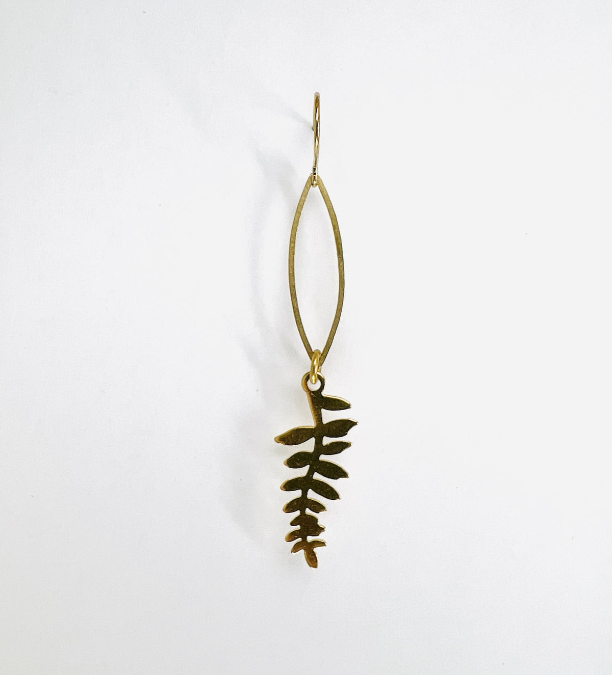 minimalist Fern leaf single gold colored earring, handcrafted nature-inspired, hanging on white background.