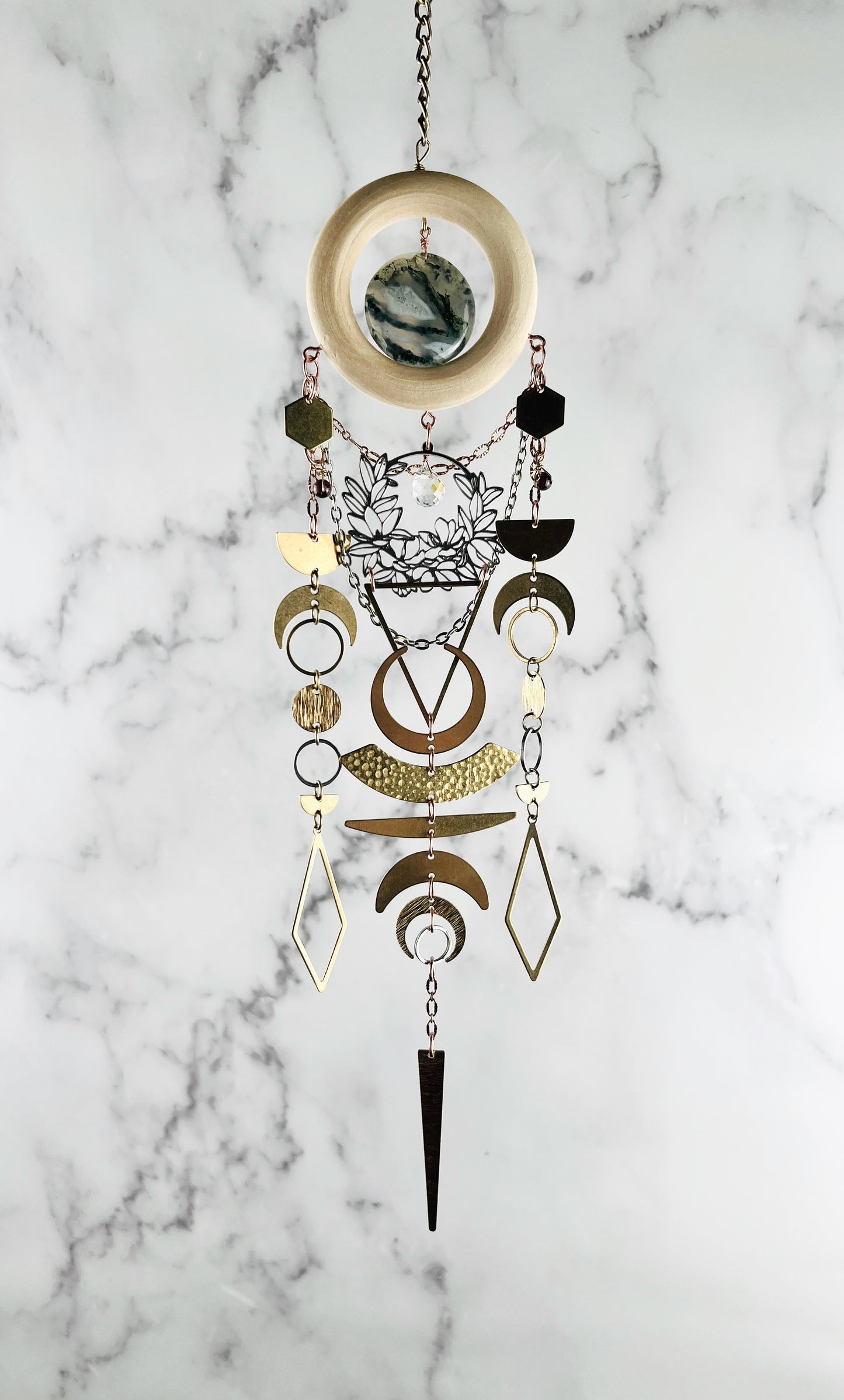 Decorative hanging art with geometric shapes-hexagon, diamond, circles, triangles, crescent moons and flowers on a marble background. Handcrafted Moss Agate and Red Garnet manifestation charm wall art created for intentional home decor and emotional balance.