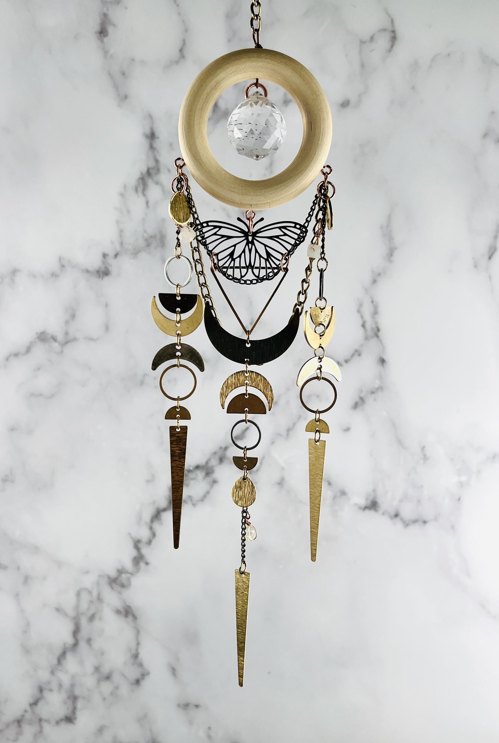 Decorative hanging art with geometric shapes, butterfly, crescent moons and crystals on a marble background. Handmade Pink Aventurine and Topaz wall art suncatcher manifestation charmwith prism, created for intentional home decor and emotional balance.